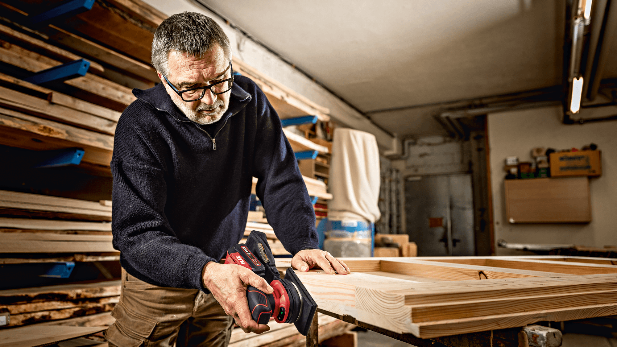 Handwerker in Werkstatt schleift eine Kante an Holzstück mit dem FLEX Akku-Schwingschleifer