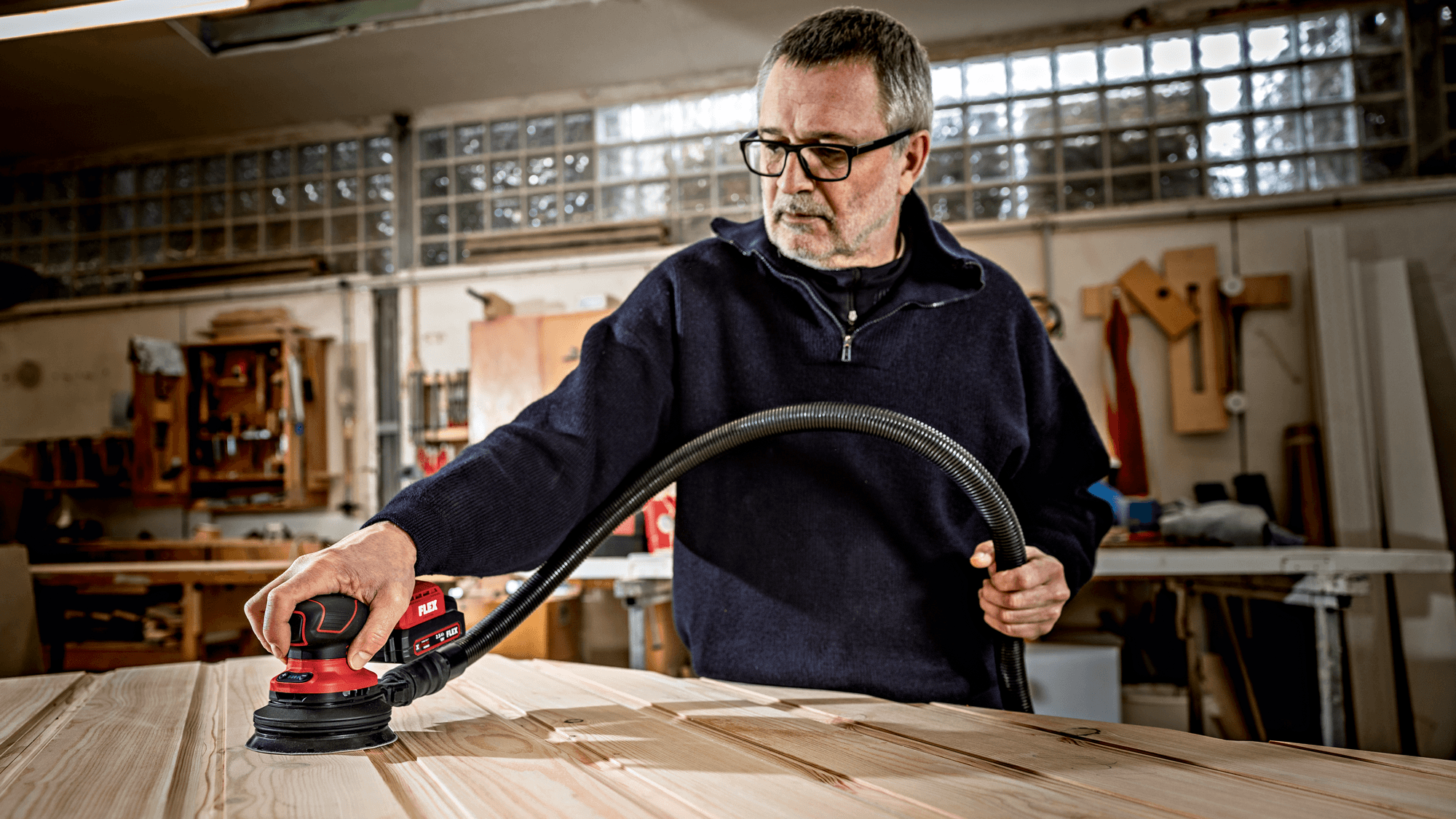 Carpenter uses the FLEX cordless random orbit sander for fine sanding in his workshop