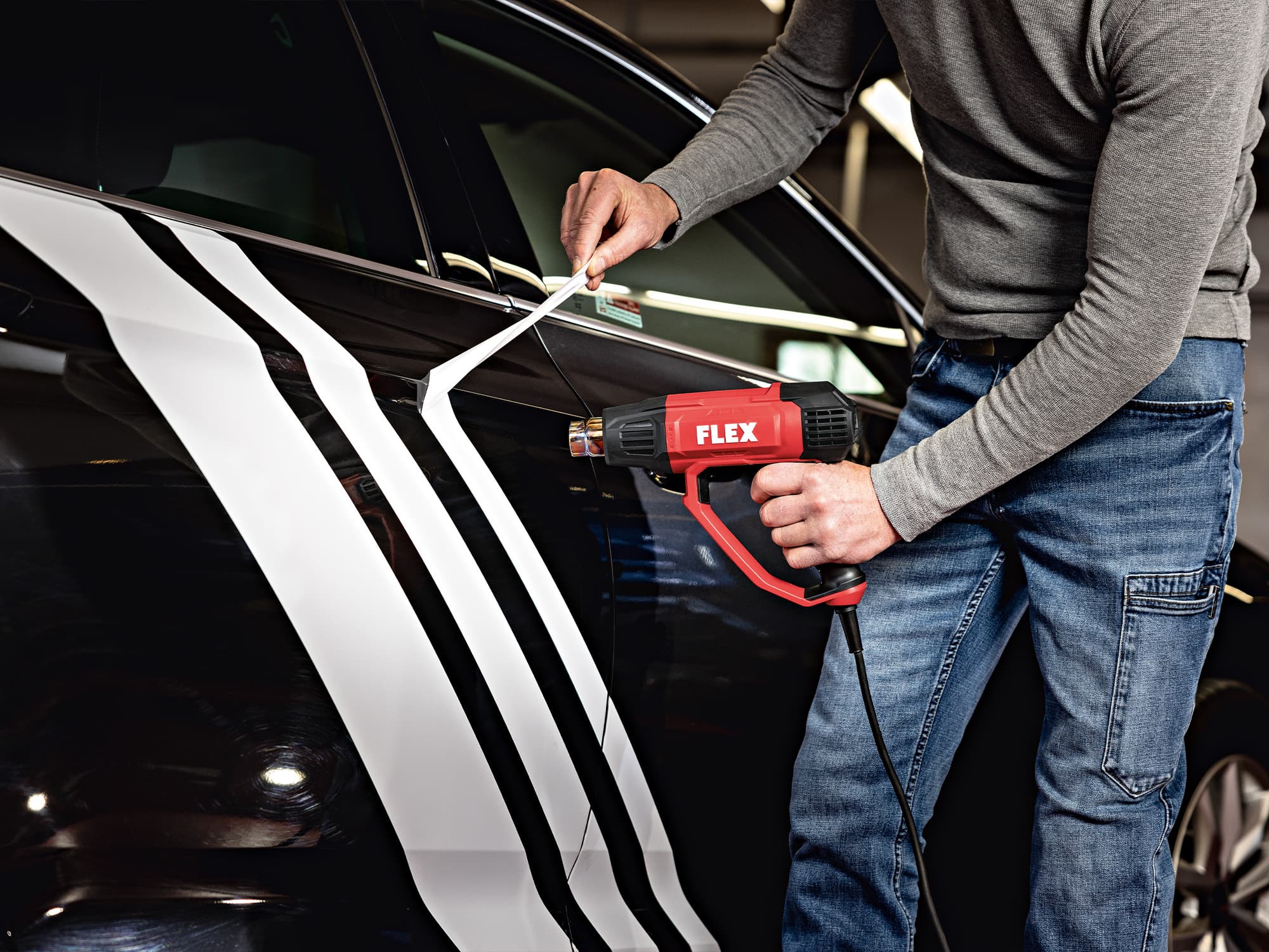 L'autocollant est retiré d'une voiture à l'aide du pistolet à air chaud HG 650 2000