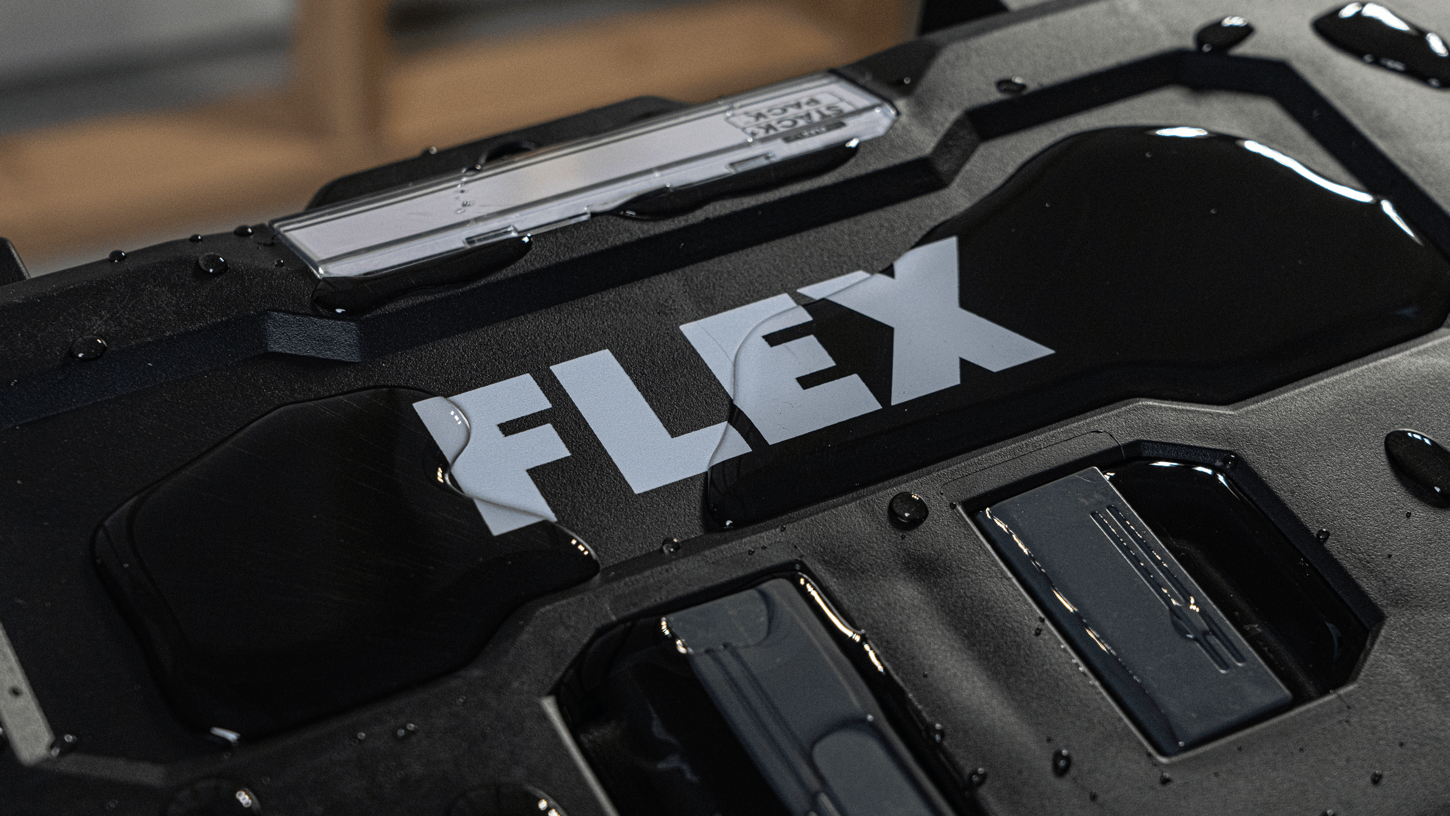 Detailný záber na prepravný kufor STACK PACK™ s logom FLEX a kvapkami vody. Robustné puzdro s krytím IP 65 zaručuje ochranu proti prachu a vode na stavenisku.
